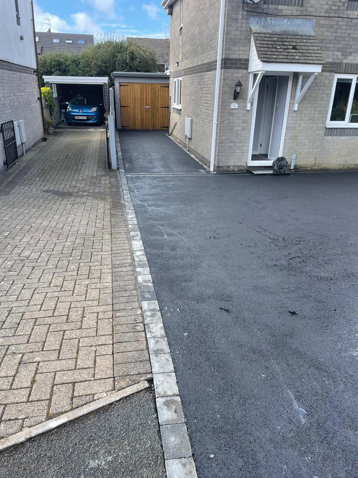 Freshly laid tarmac driveway beside a brick house